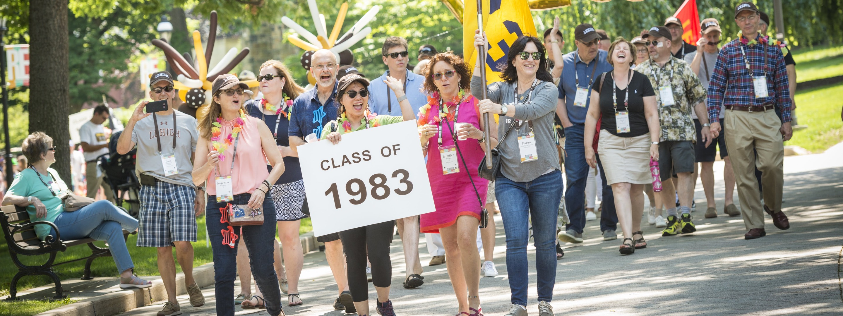 Picture of Lehigh Alumni walking on Lehigh's campus, holding a sign "Class of 1983"